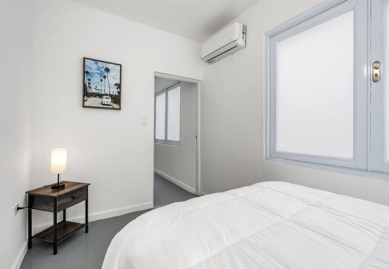Queen bed beside a bright window