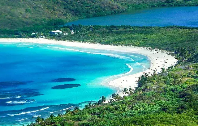 A stunning tropical beach with white sand, turquoise waters, and a clear blue sky.