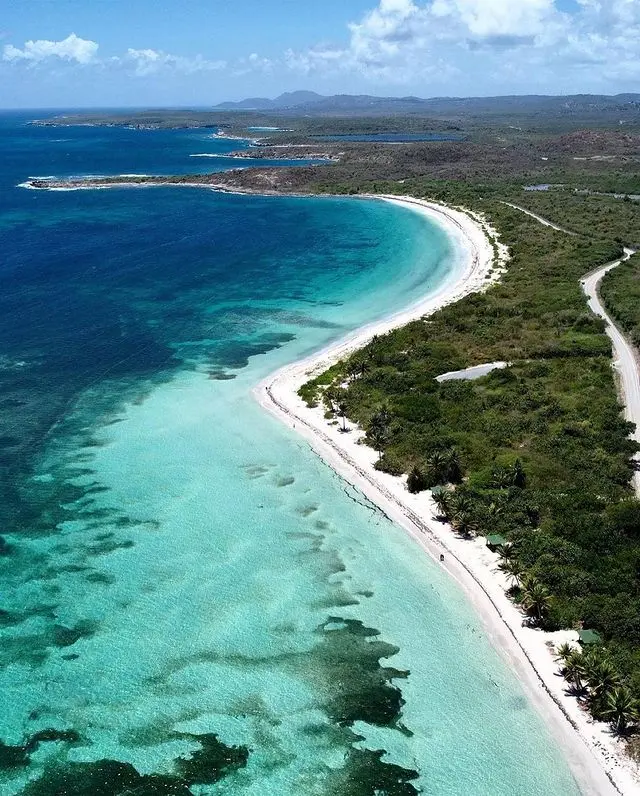 The clear, blue waters of Flamenco Beach are calm and inviting for swimming and wading, complemented by a vast expanse of white sand ideal for sunbathing and leisurely walks.